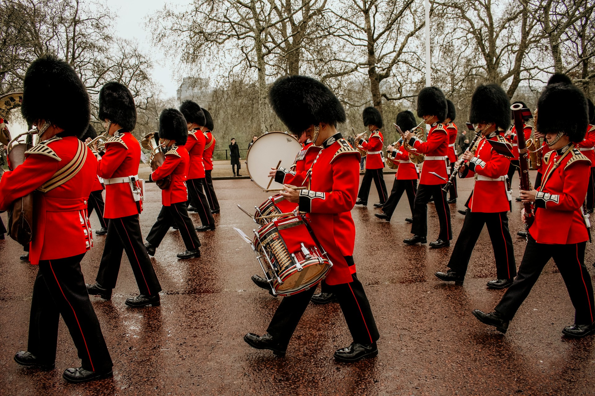 A marching band in red uniforms and black bearskin hats parading on a street. | Photo by Morgan Skinner on Unsplash