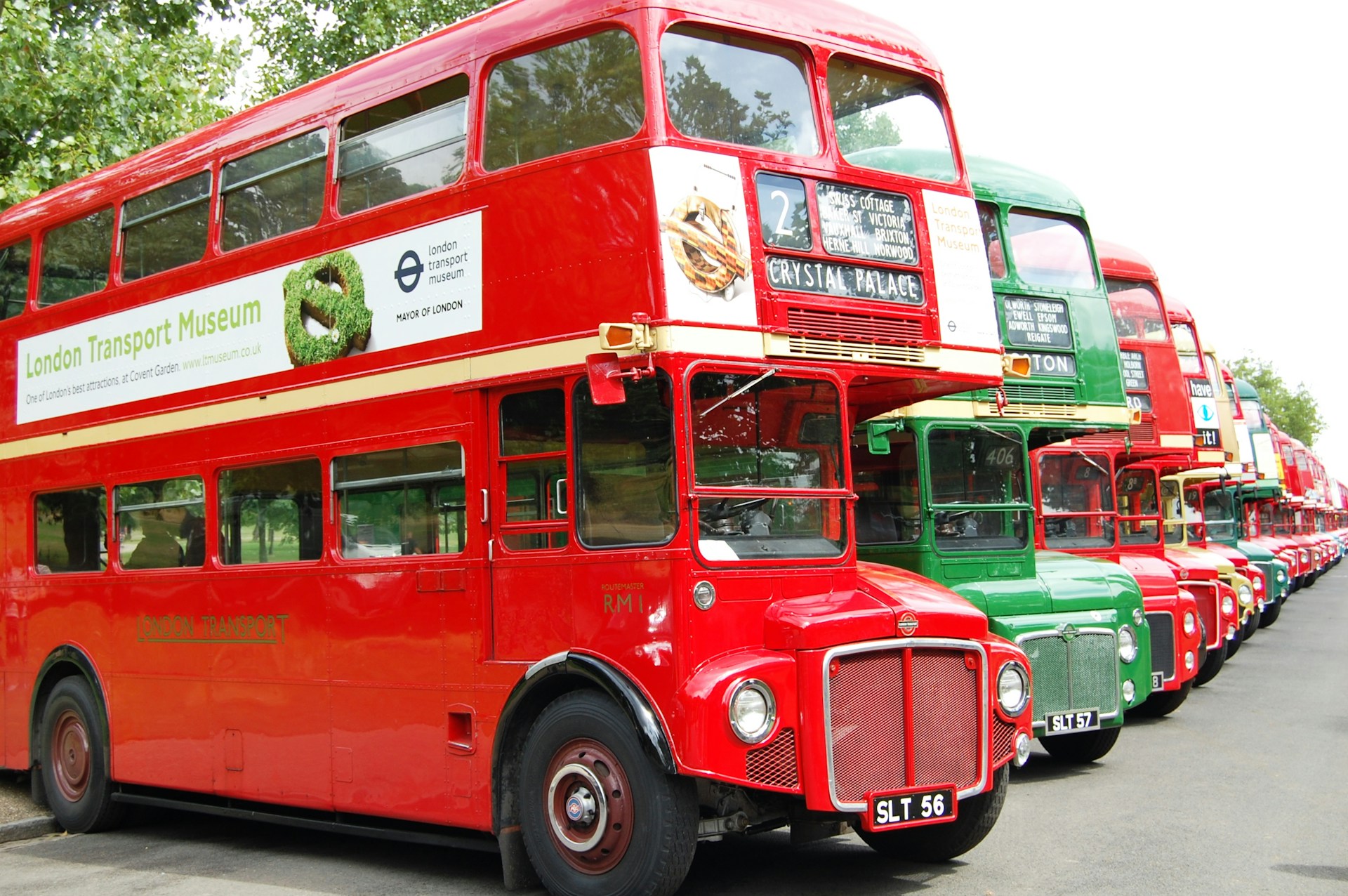 A row of red vintage double-decker buses lined up on a London street. | Photo by Jude Mack on Unsplash