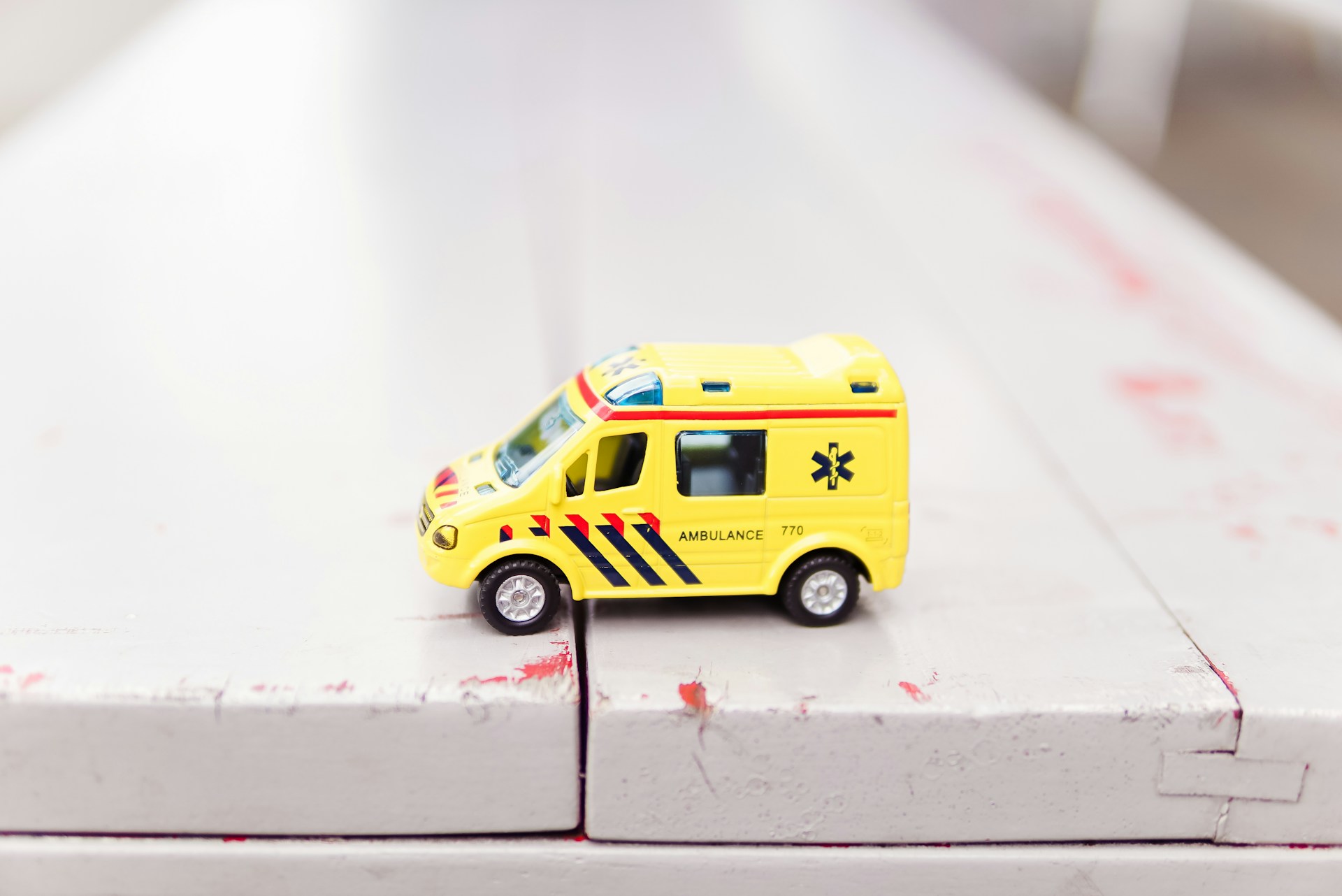 Toy ambulance on a white surface with soft focus background. | Photo by Zhen H on Unsplash