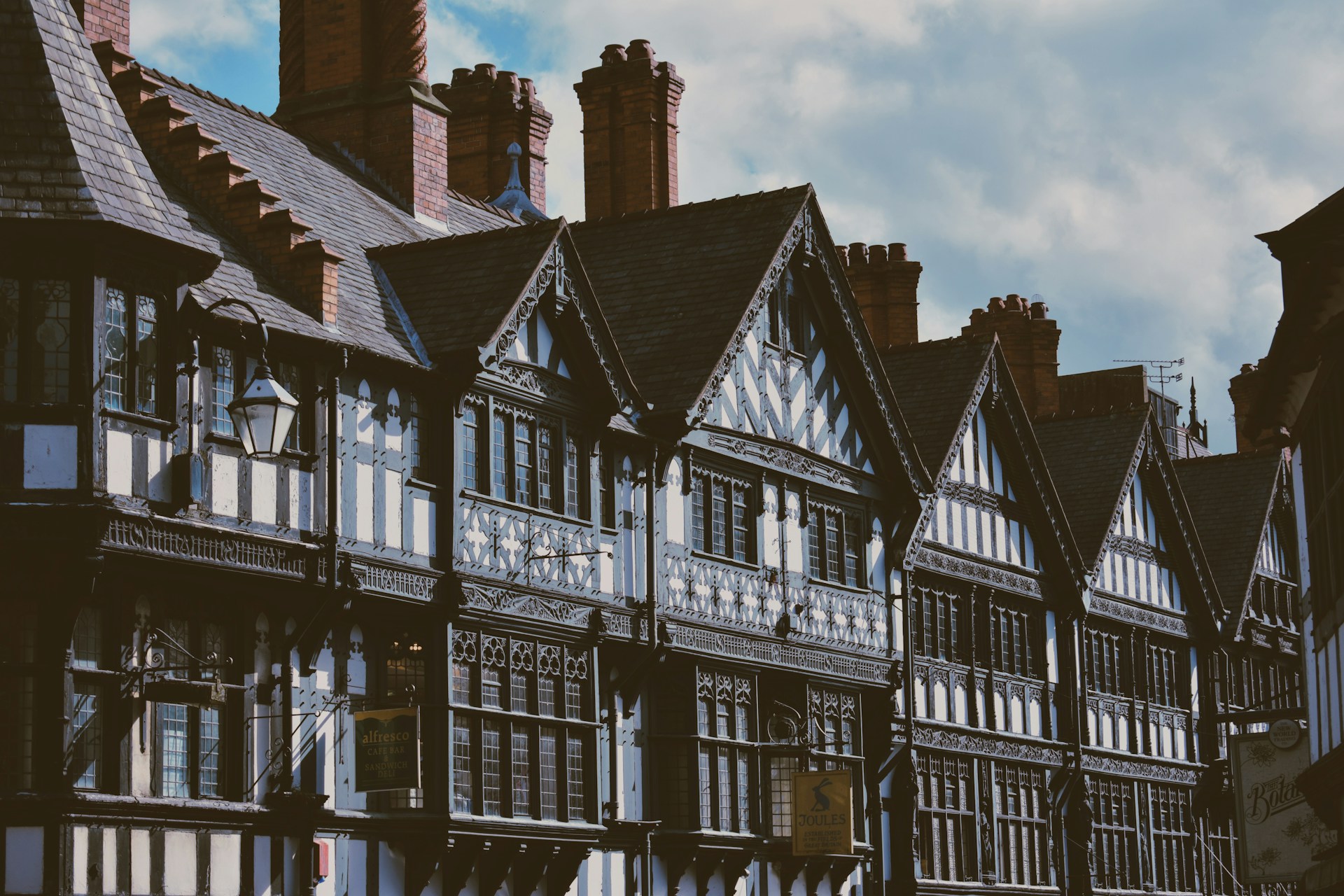 Half-timbered Tudor-style black and white buildings under a cloudy sky. | Photo by Mitch Rosen on Unsplash