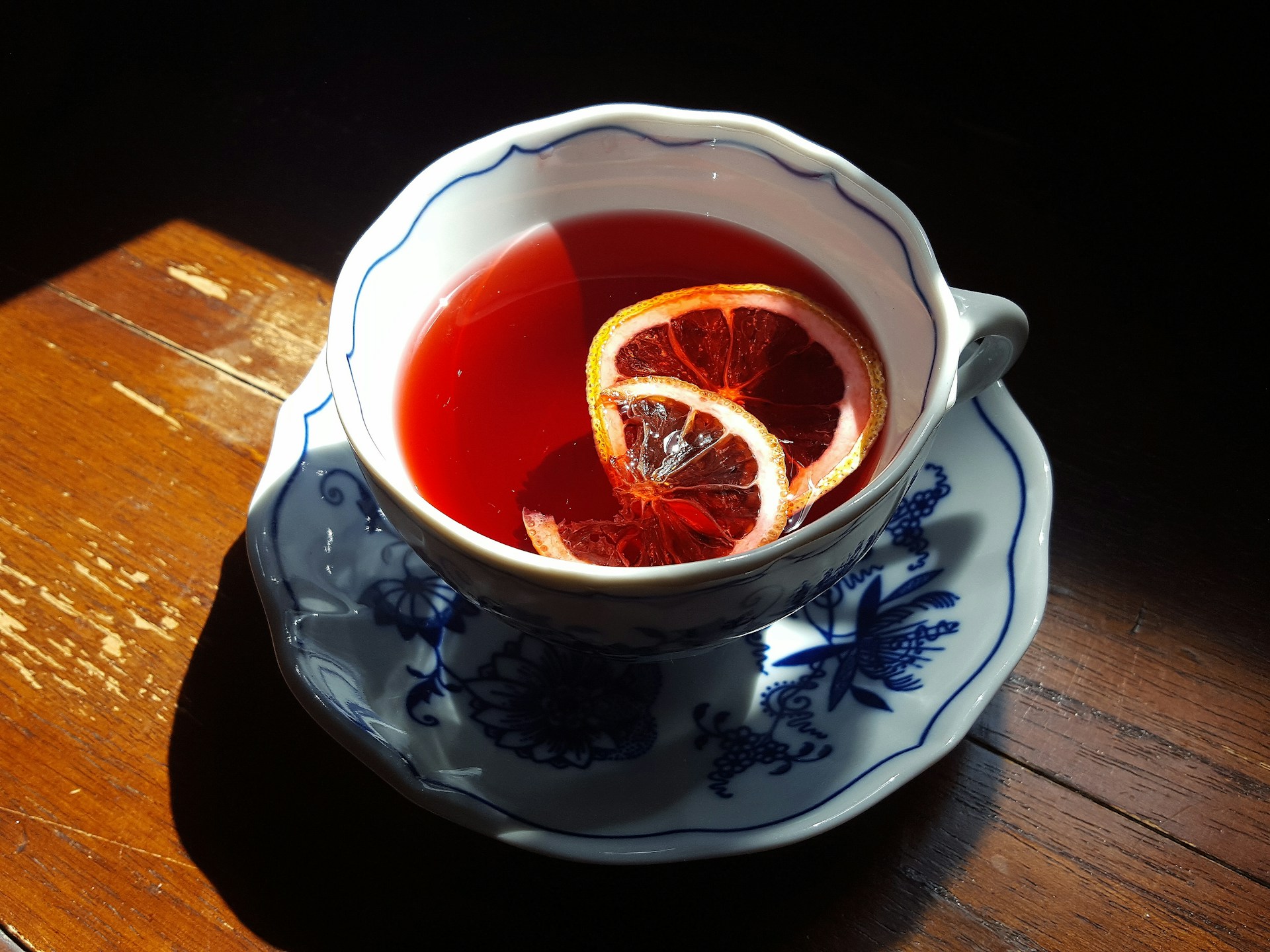 A cup of tea with a slice of lemon on a saucer, illuminated by sunlight. | Photo by TEAcreativelife │ Soo Chung on Unsplash