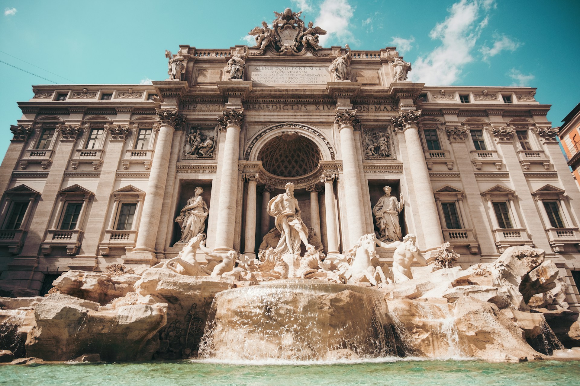 Baroque fountain with sculptures and clear blue water under a bright sky. | Photo by Cristina Gottardi on Unsplash
