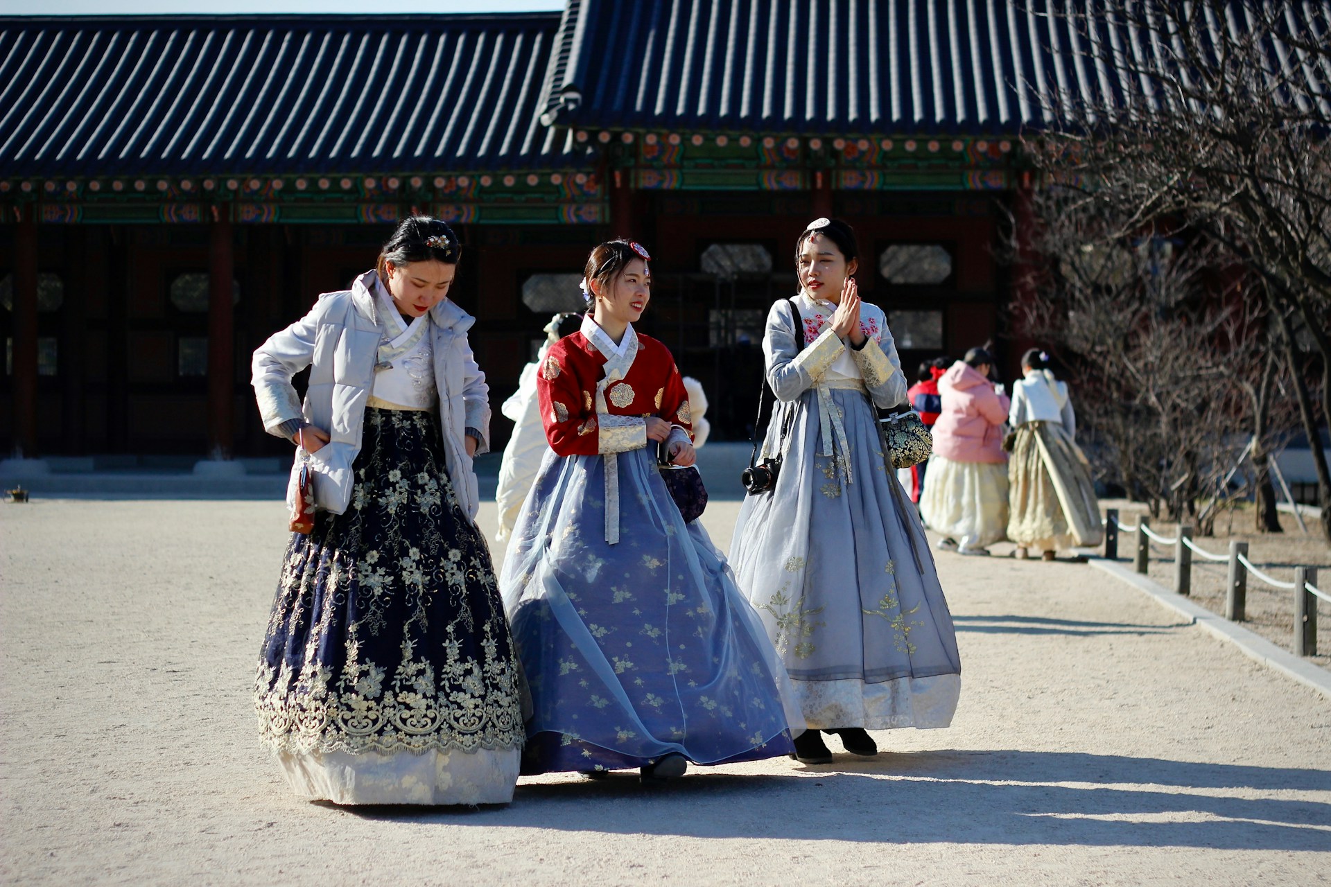 Three individuals in traditional Korean Hanbok dresses at a cultural site. | Photo by Kseniya Petukhova on Unsplash