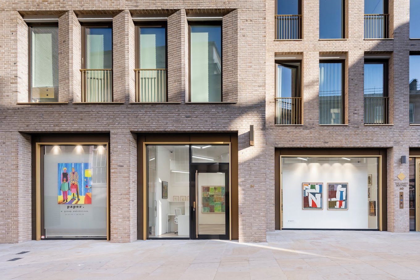 Modern brick building facade with gallery storefronts displaying colorful artwork. | 2024 Beers London