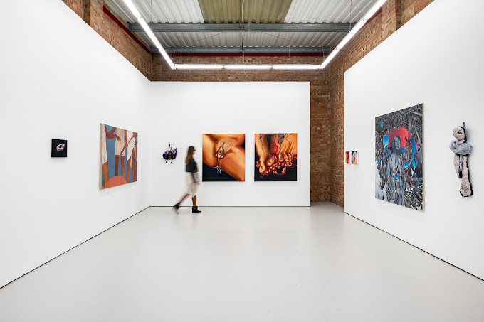 Modern art gallery interior with various paintings and one person walking by. | Anna Kultys Gallery