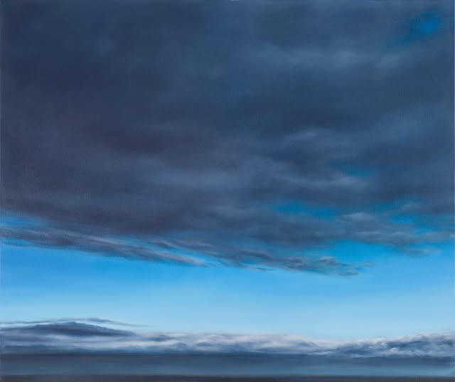 A serene sky displays dark clouds blending into a bright blue background, evoking a tranquil yet dramatic atmosphere.