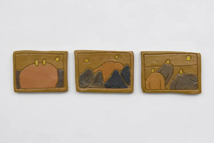 Three textured clay panels depicting abstract landscape scenes with hills, a sun, and warm earth-toned colors.