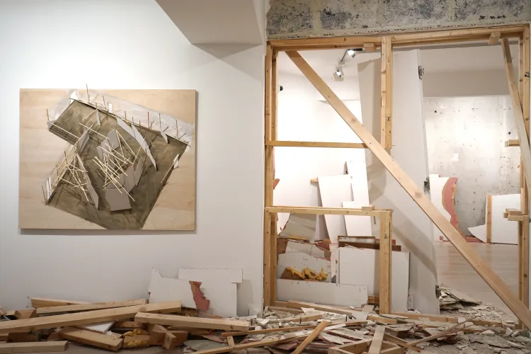 An abstract art piece on the wall beside a construction site, showcasing wooden beams and debris scattered on the floor.