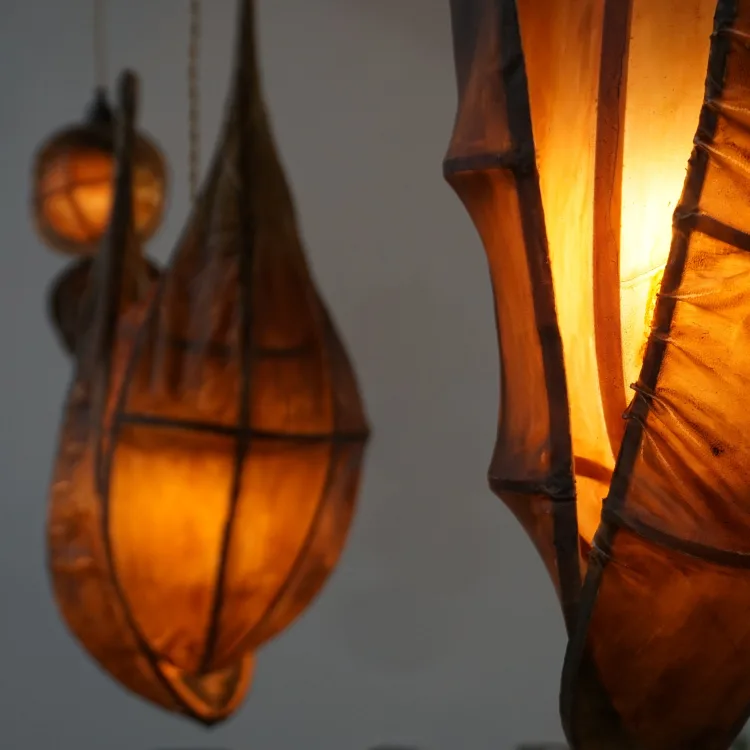 Two warm-toned, intricately designed hanging lanterns illuminate a softly blurred background, creating a cozy ambiance.