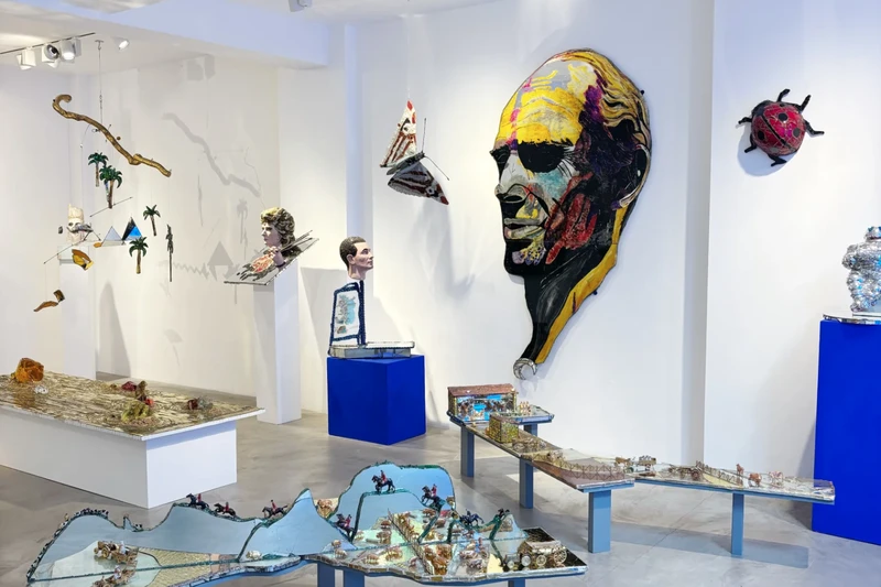A room showcasing a diverse array of objects mounted on the wall, including artwork and a LEGO display, typical of a museum exhibition.