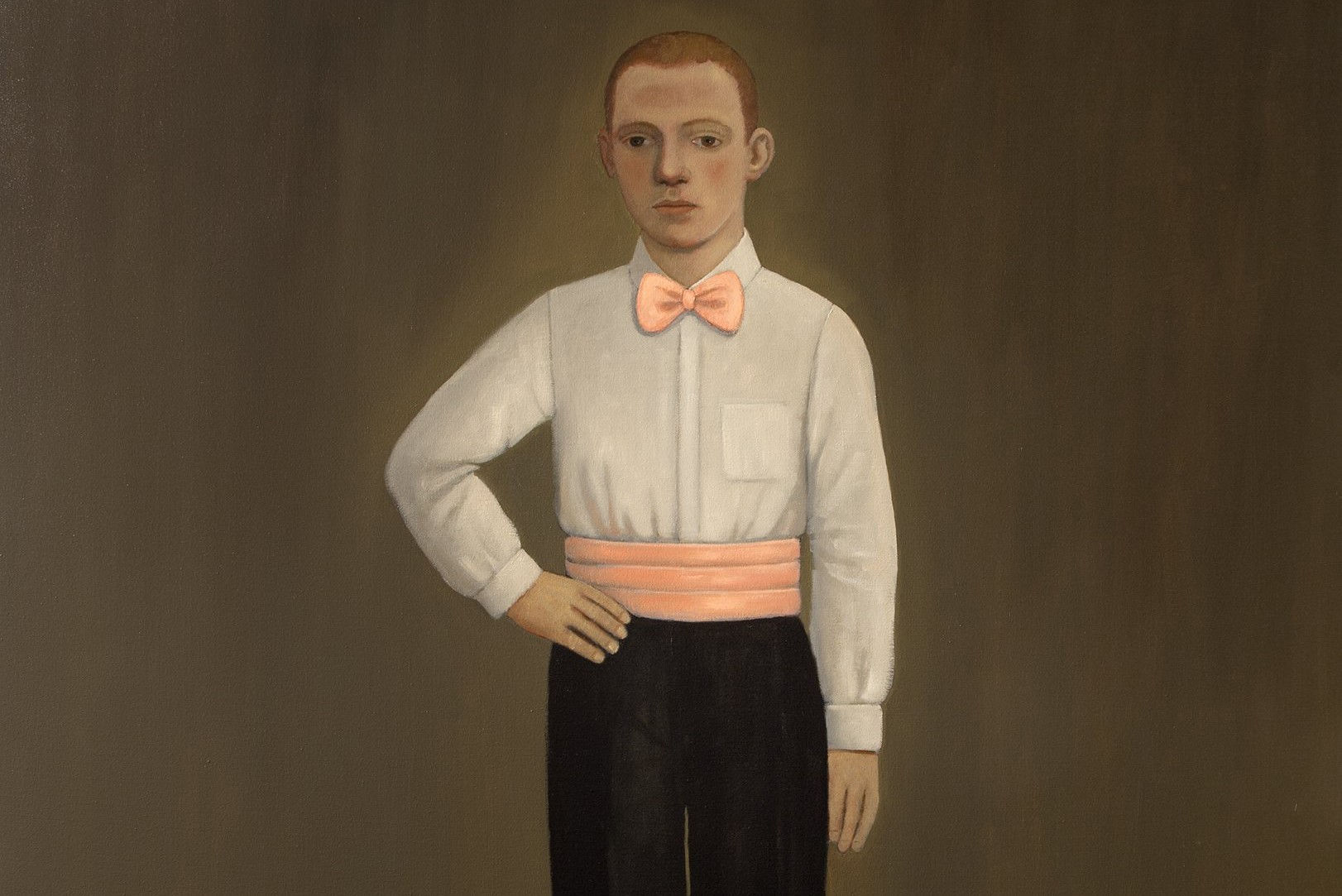 A young boy stands confidently with one hand on his hip, wearing a white dress shirt with a bow tie and black pants. The background is a muted tone, highlighting the figure.