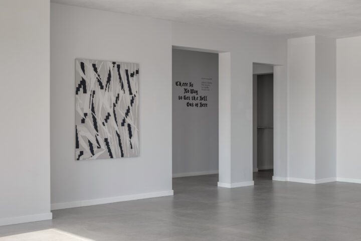 A minimalist interior space with white walls, featuring an abstract black and white painting on one wall and a doorway leading to another room.