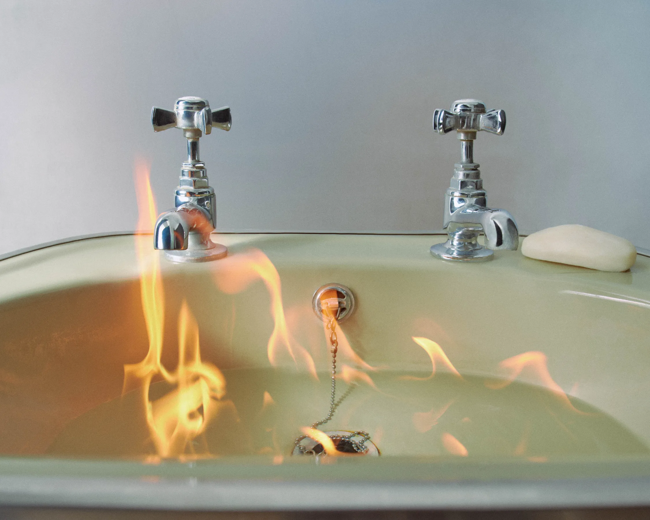 A bathroom sink with flames emerging from the drain.