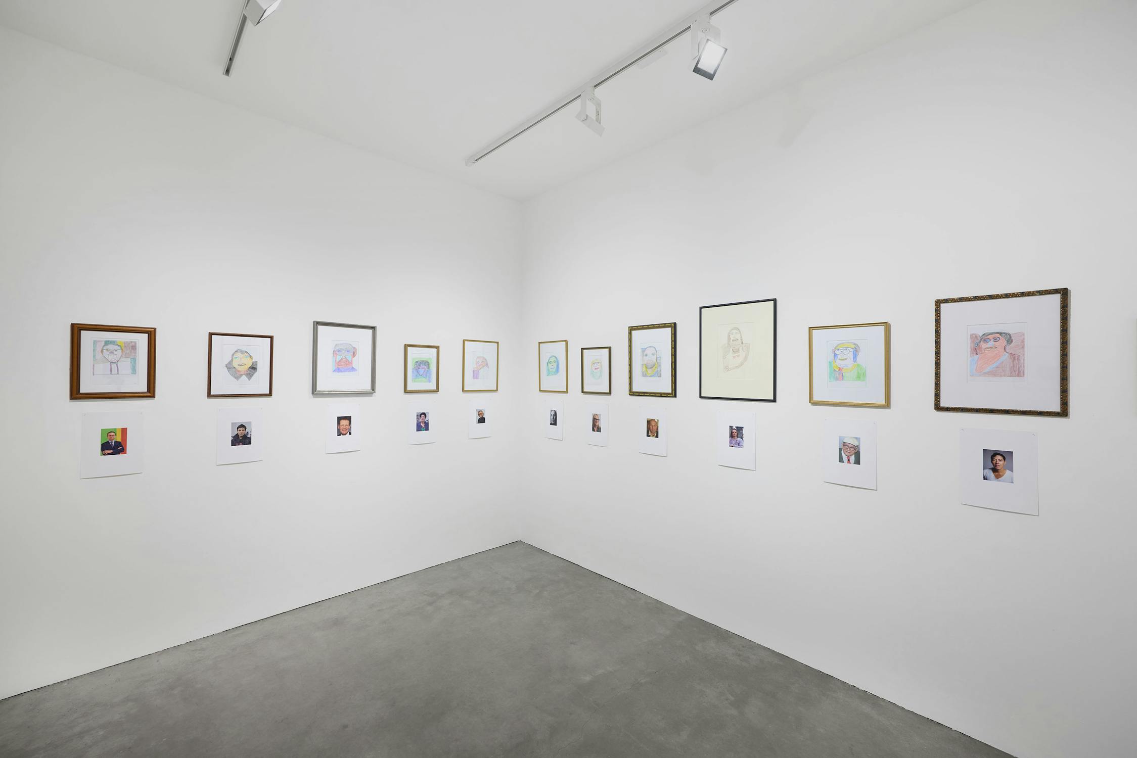 A gallery wall displaying framed artworks and photographs in a white room.